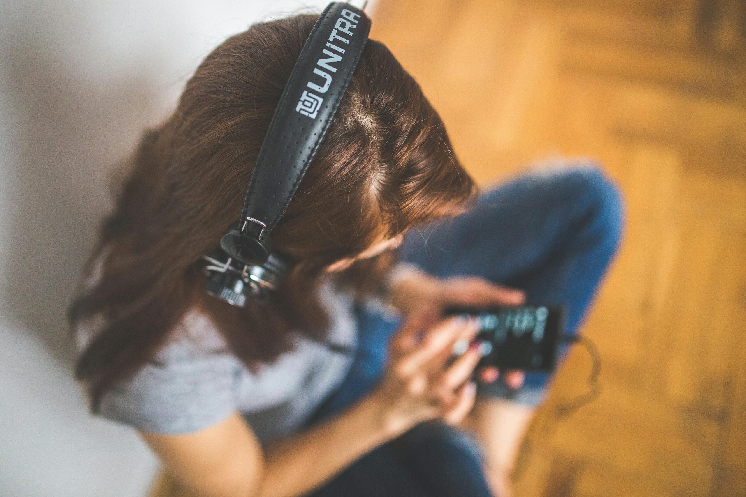 Top view of a woman using a smartphone and listening to music with headphones.